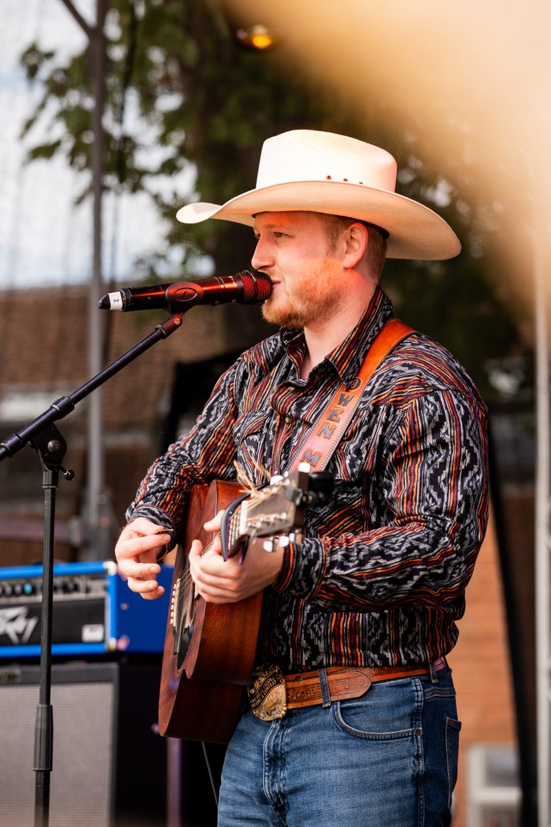 Singer in a white cowboy hat performing with guitar