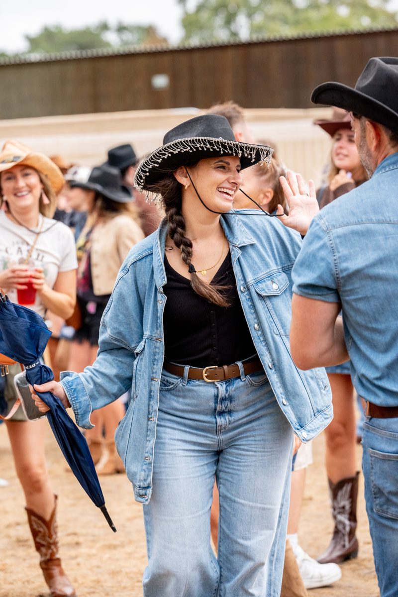 Festival-goer in denim and a black cowboy hat dancing in the crowd